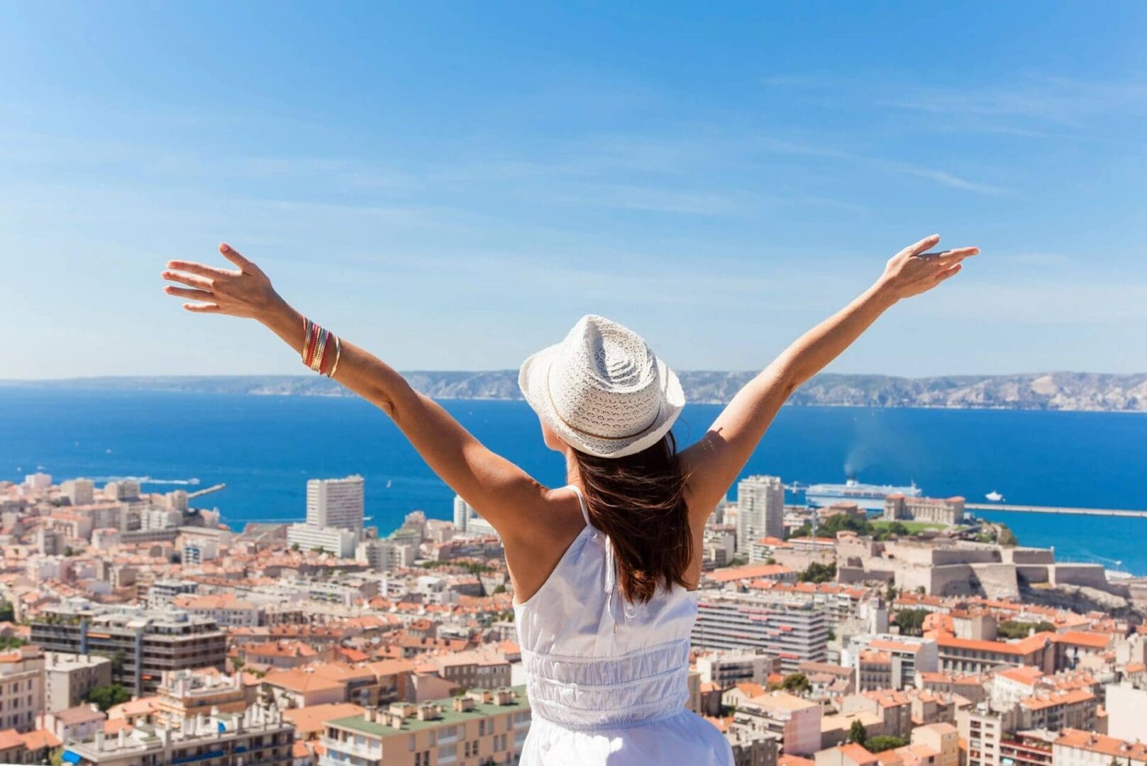 A woman in white shirt and hat raising her arms.